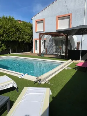 a swimming pool with an umbrella next to a house at La casemate in LʼIsle-sur-la-Sorgue
