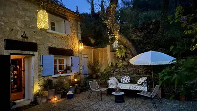 a patio with a table and chairs and an umbrella at Charmant mas perché en Provence in Saumane-de-Vaucluse