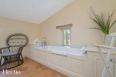 a large white bathroom with a tub and a chair at Château Constantin in Cadenet