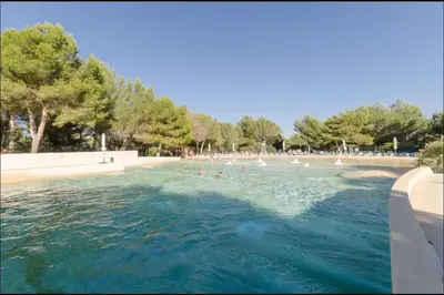 a swimming pool with people in the water at Appartement Pont Royal vu lac in Mallemort
