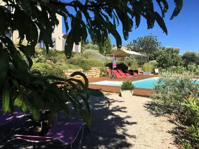 a swimming pool in a yard with two chairs and a person at Le mas Donalia in Saint-Saturnin-les-Apt