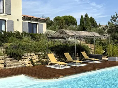 a group of chairs and an umbrella next to a swimming pool at Le mas Donalia in Saint-Saturnin-les-Apt