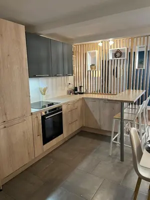 a kitchen with wooden cabinets and a table in it at L'Odelisle Appartement plein centre avec terrasse in LʼIsle-sur-la-Sorgue