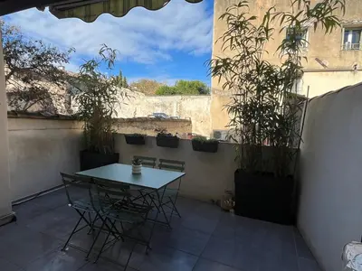 a table and chairs on a patio with potted plants at L'Odelisle Appartement plein centre avec terrasse in LʼIsle-sur-la-Sorgue