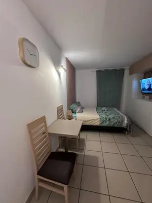 a bedroom with a bed and a table and a clock at Le Clos d'AIX studio 211 in Aix-en-Provence