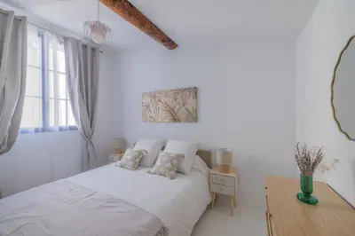 a white bedroom with a bed and a wooden table at Appartement Belle Lettre 8 in Aix-en-Provence