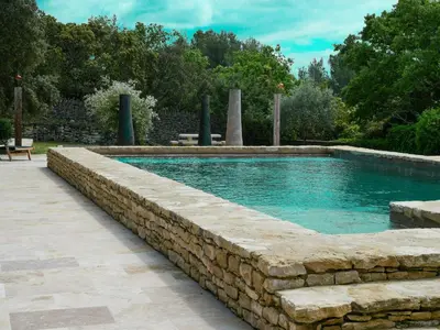 a swimming pool with a stone retaining wall at Stunning Stone House With Pool Near Gordes in Gordes