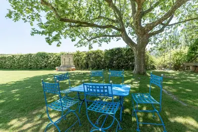 a blue table and chairs sitting under a tree at Mas, Padel privé, tennis privé, piscine 22m , Alpilles Provence in Orgon