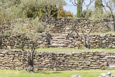 a stone wall with two trees in front of it at Mas, Padel privé, tennis privé, piscine 22m , Alpilles Provence in Orgon