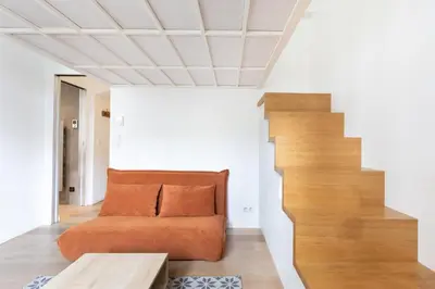 an orange couch in a room with a staircase at Le Zola - Studio premium hypercentre - Wifi - Climatisation in Aix-en-Provence