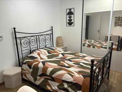 a bedroom with a bed with a comforter and a mirror at Grande maison familiale tout confort in Éguilles