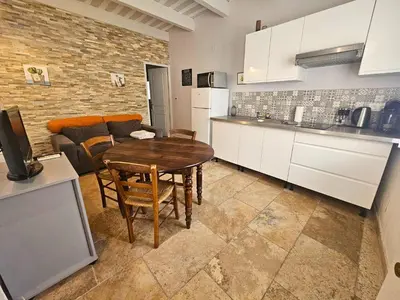 a kitchen and living room with a table and a couch at Au coeur de la Venise Povençale in LʼIsle-sur-la-Sorgue