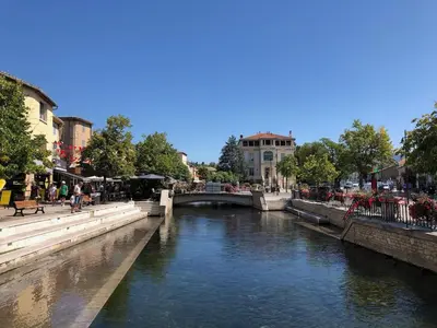 a river in a city with a bridge at Magnifique appartement au cœur de la Venise Provençale in LʼIsle-sur-la-Sorgue