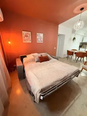 a bedroom with a bed with an orange wall at Appartement de la flûte in LʼIsle-sur-la-Sorgue