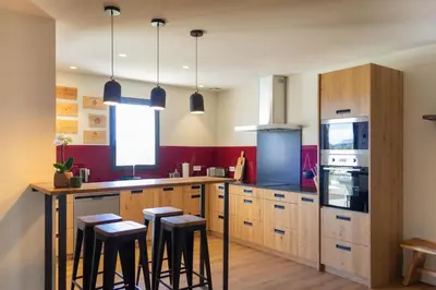 a kitchen with wooden cabinets and a counter with stools at La Maison De Paulette in Joucas