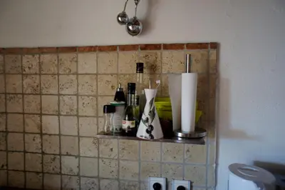 a shelf on a tiled wall with bottles on it at La Bergerie de Saignon in Saignon