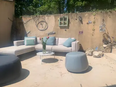 a patio with a couch and a table and two stools at La Bergerie de Saignon in Saignon