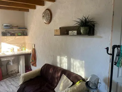 a living room with a couch and a clock on the wall at studio à la campagne avec piscine in Peyrolles-en-Provence