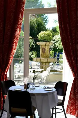 a white table with wine glasses and a large window at Grand Hôtel Henri - Teritoria in LʼIsle-sur-la-Sorgue