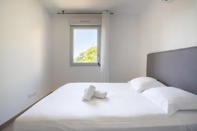 a bedroom with a white bed with a window at Le Casanelle in Aix-en-Provence