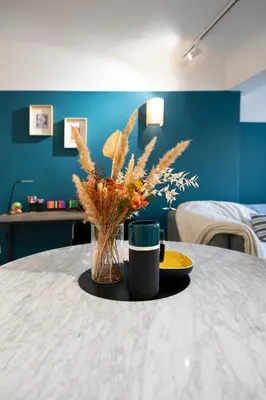 a table with a vase of flowers and a coffee mug at 2 rooms apartment in the city center in Aix-en-Provence