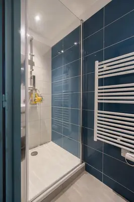 a bathroom with a shower with blue tiles at 2 rooms apartment in the city center in Aix-en-Provence