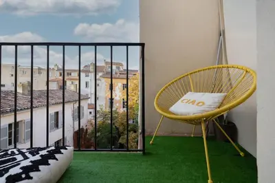 a yellow chair sitting in front of a large window at 2 rooms apartment in the city center in Aix-en-Provence