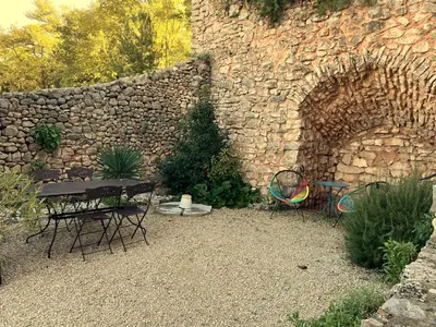 a table and chairs in front of a stone wall at Gîte au Ventoux in Villes-sur-Auzon