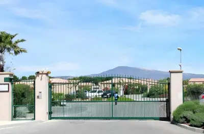 a gate in front of a building with mountains in the background at Maison Les Demeures du Ventoux in Aubignan