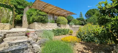a garden with a stone wall and some plants at mas des oliviers in Gordes