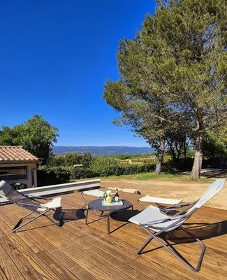 two chairs and a table on a wooden deck at Villa grand confort, piscine privée, petanque, pool house in Alleins