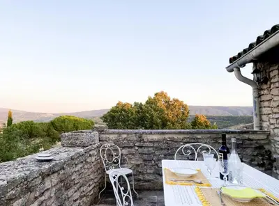 a table and chairs on a stone wall at Stone House Within Castle Ramparts In Goult in Goult