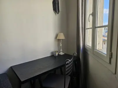 a desk with a lamp and a chair next to a window at Duplex entre Palais de justice et Cours Mirabeau, Climatisation in Aix-en-Provence
