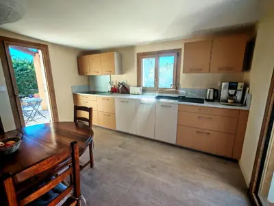 a kitchen with a wooden table and a table and a dining room at Villa provençale Les Agapanthes in Saint-Saturnin-les-Apt