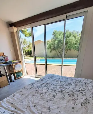 a bedroom with a bed and a view of a pool at Le Jardin du Félibrige in Lançon-Provence