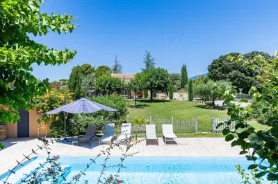 a patio with chairs and an umbrella next to a pool at Villa A l'ombre du Géant climatisée piscine pour 8 personnes in Saint-Pierre-de-Vassols
