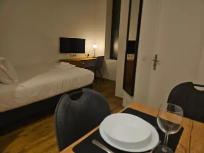 a room with a bed and a table with a white plate on it at La Bastide Foch - Appart'Hôtel Calme & Confort Centre Ville in Salon-de-Provence