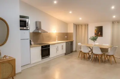 a kitchen with a wooden table and white cabinets at Charmant appartement au centre ville de Cavaillon in Cavaillon