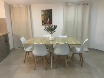 a dining room with a wooden table and white chairs at Charmant appartement au centre ville de Cavaillon in Cavaillon