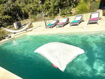 a swimming pool with lounge chairs in the water at cheznico jas d la plane in Bédoin