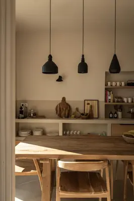 a kitchen with a wooden table and black pendant lights at Maison Rosalie in Carpentras