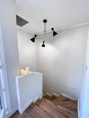 a room with a white wall and a chandelier at La Terrasse, 2 chambres, hyper centre in Aix-en-Provence