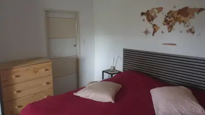 a bedroom with a red bed and a map of the world on the wall at Petite maison sur Apt in Apt