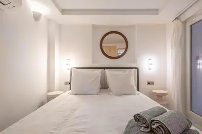 a white bedroom with a large bed with a mirror at Logement elegant avec patio prive et climatisation in Aix-en-Provence