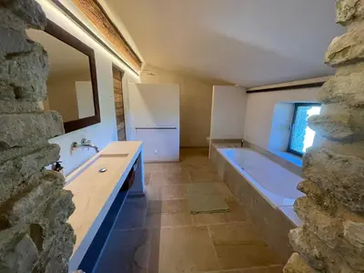 a bathroom with a tub and a sink and a mirror at Le Jas à Goult in Goult