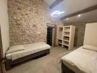 a bedroom with two beds and a stone wall at Le Jas à Goult in Goult