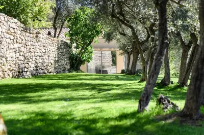 a garden with a stone wall and trees at Le Hameau des Sources Lourmarin Luberon in Lourmarin
