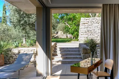 a glass door leading to a patio with a table and chairs at Le Hameau des Sources Lourmarin Luberon in Lourmarin
