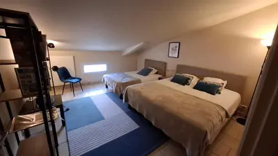 a hotel room with two beds and a chair at Ginette et Marcel la maison in Saint-Rémy-de-Provence