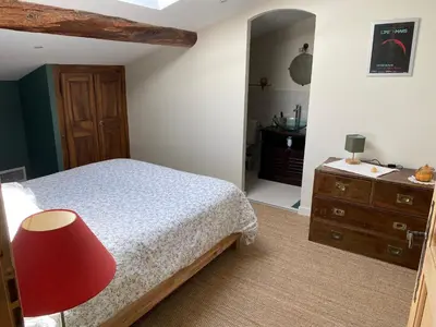a bedroom with a bed and a red chair at Casa Poli, maison de village avec terrasse in Eyguières